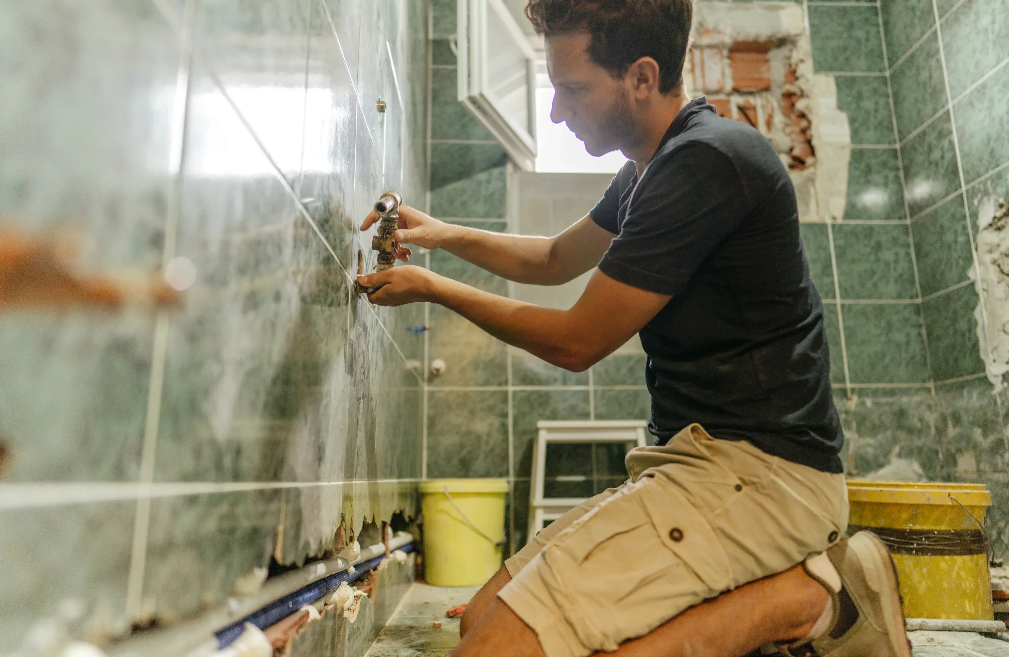 Professional bathroom renovation in Gold Coast showing plumbing installation, tile removal, and waterproofing work by licensed tradespeople