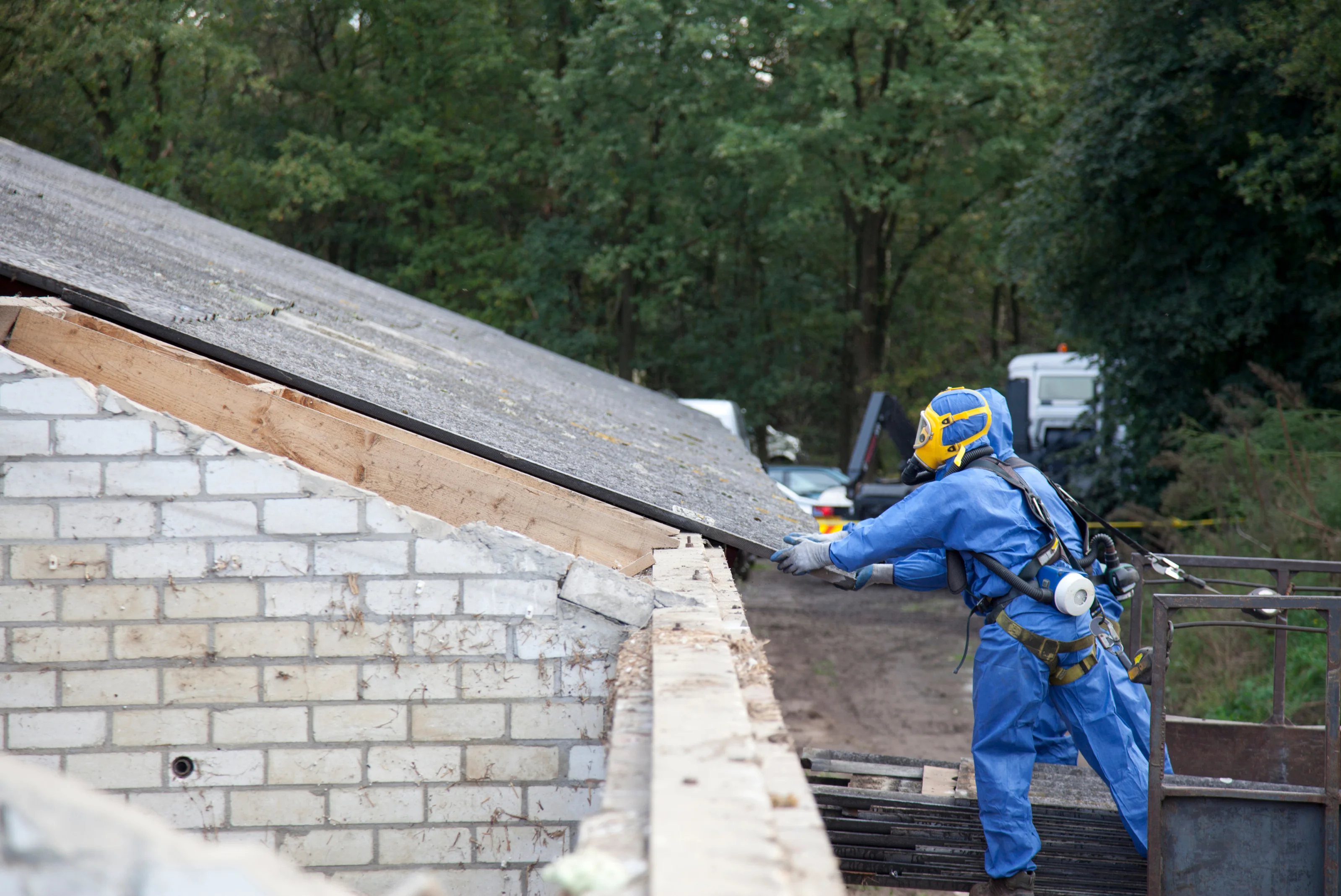 Licensed contractor performing asbestos roof removal with proper safety equipment